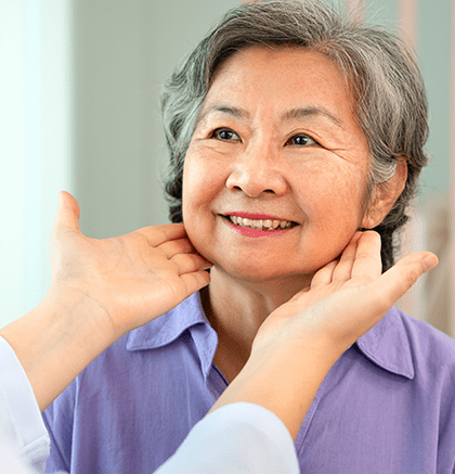 Dermatologist examining older woman with aging skin around her eyes during consultation
