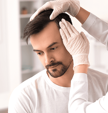 Dermatologist examining male patient’s scalp for alopecia areata