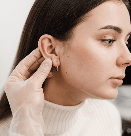 Dermatologist examining patient’s ear for keloid scar